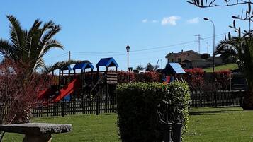Enjoy a peaceful retreat in a serene park setting with a playground, lawn, and bench.