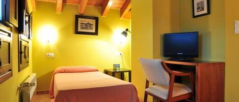 A hotel room with two beds, a desk with a chair, a television, and framed pictures on the wall.