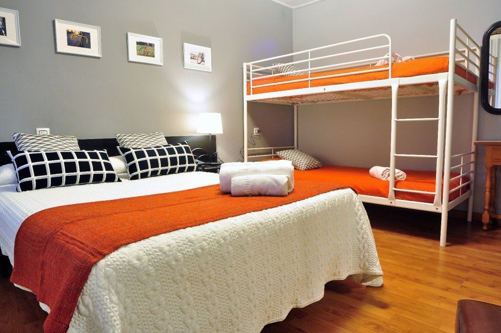 Ein Zimmer mit einem Etagenbett, einem Einzelbett und einem Schreibtisch mit Lampe.