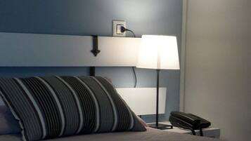 A bed with a striped pillow, a bedside lamp, and a phone on a nightstand.