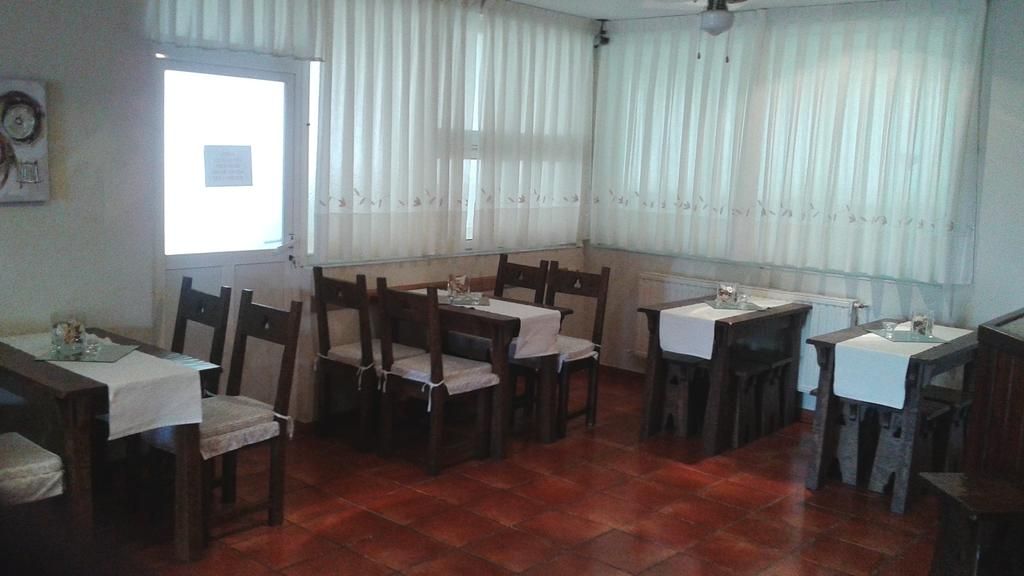 Un espace repas avec des tables et des chaises en bois, une fenêtre avec des rideaux et un sol carrel é.