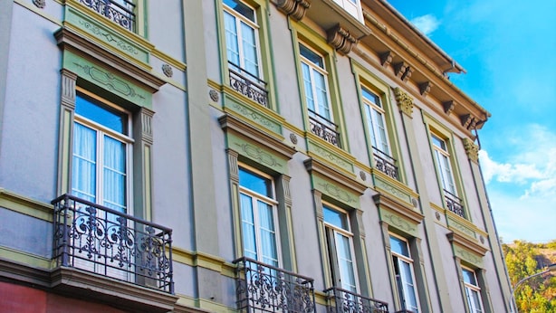 A multi-story building with ornate architectural details, including decorative moldings and a balcony with wrought iron railings. - La Colmena (Valdes)