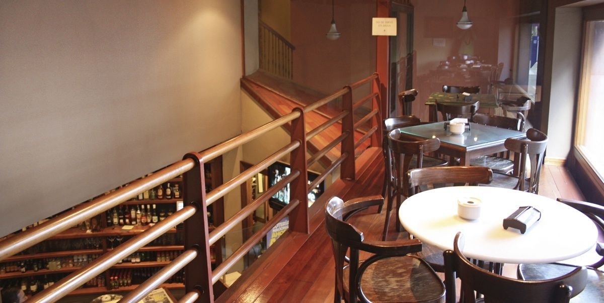 A restaurant with a wooden staircase, round tables, and chairs.