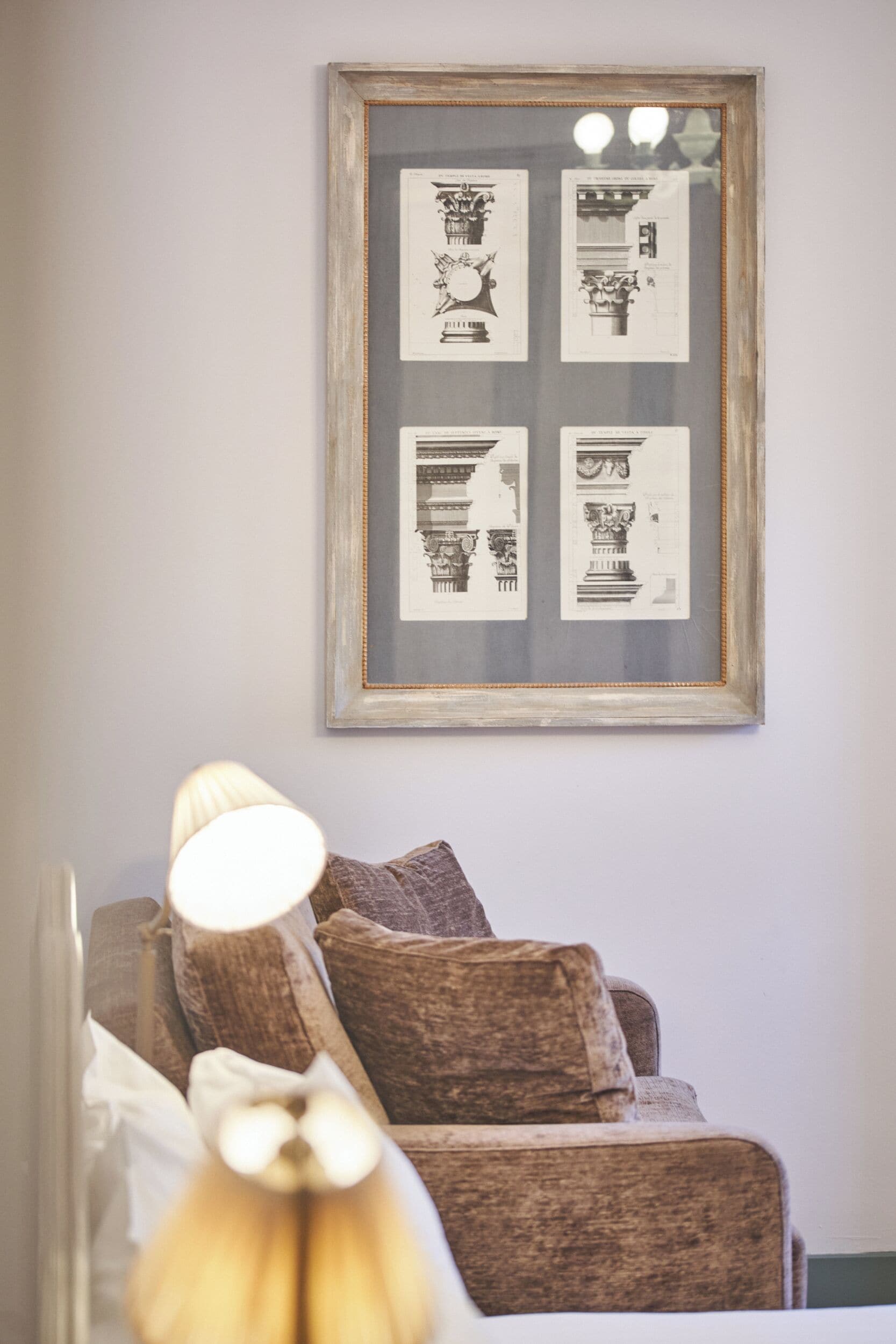 A framed architectural drawing on a wall, a sofa with cushions, and a lamp.