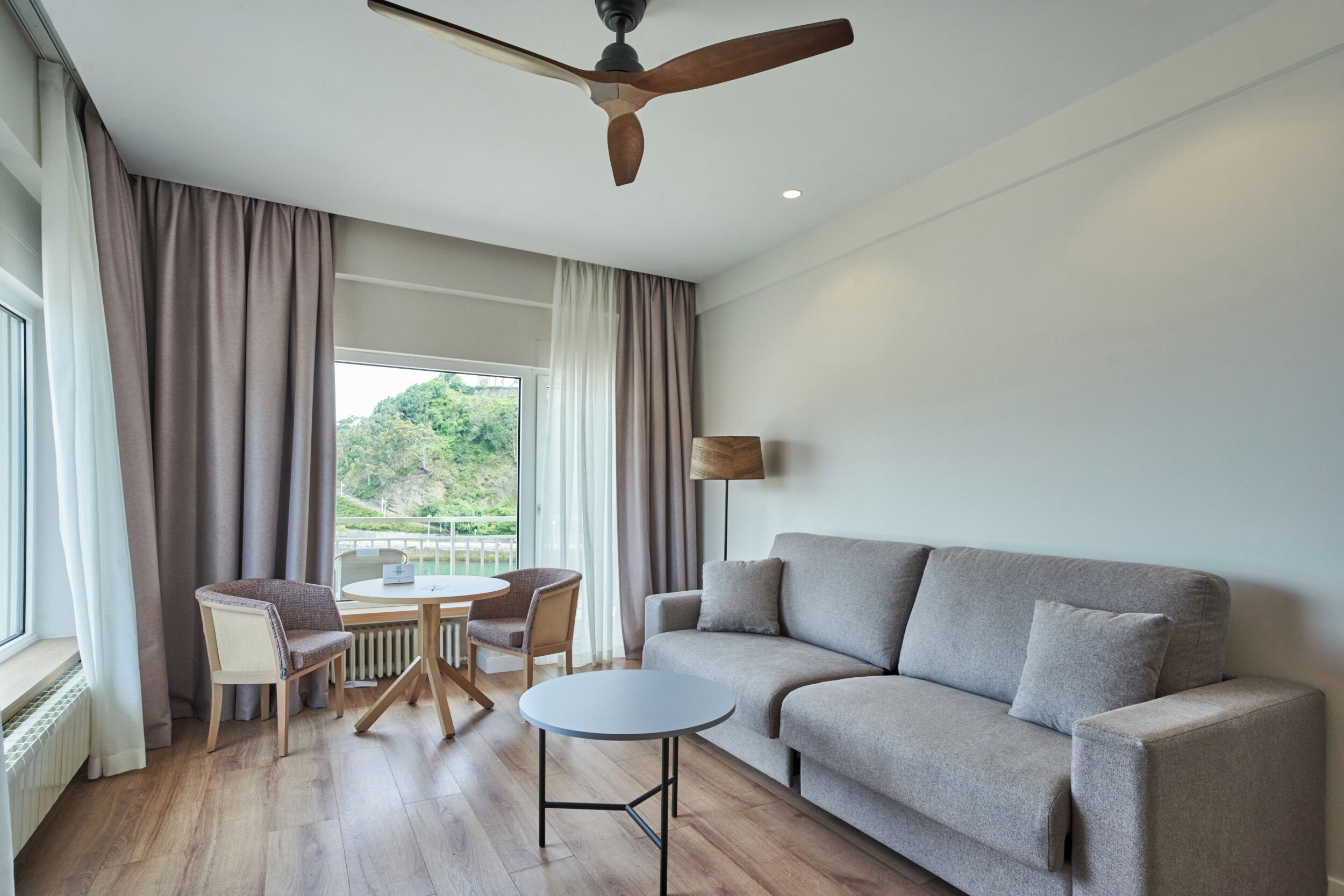 Uma sala de estar moderna com um sofá, uma mesa redonda e um ventilador de teto.