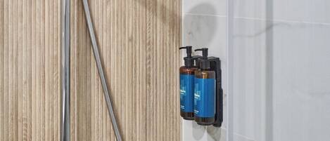 A shower with a handheld showerhead, a wall-mounted control panel, and a glass shower enclosure.