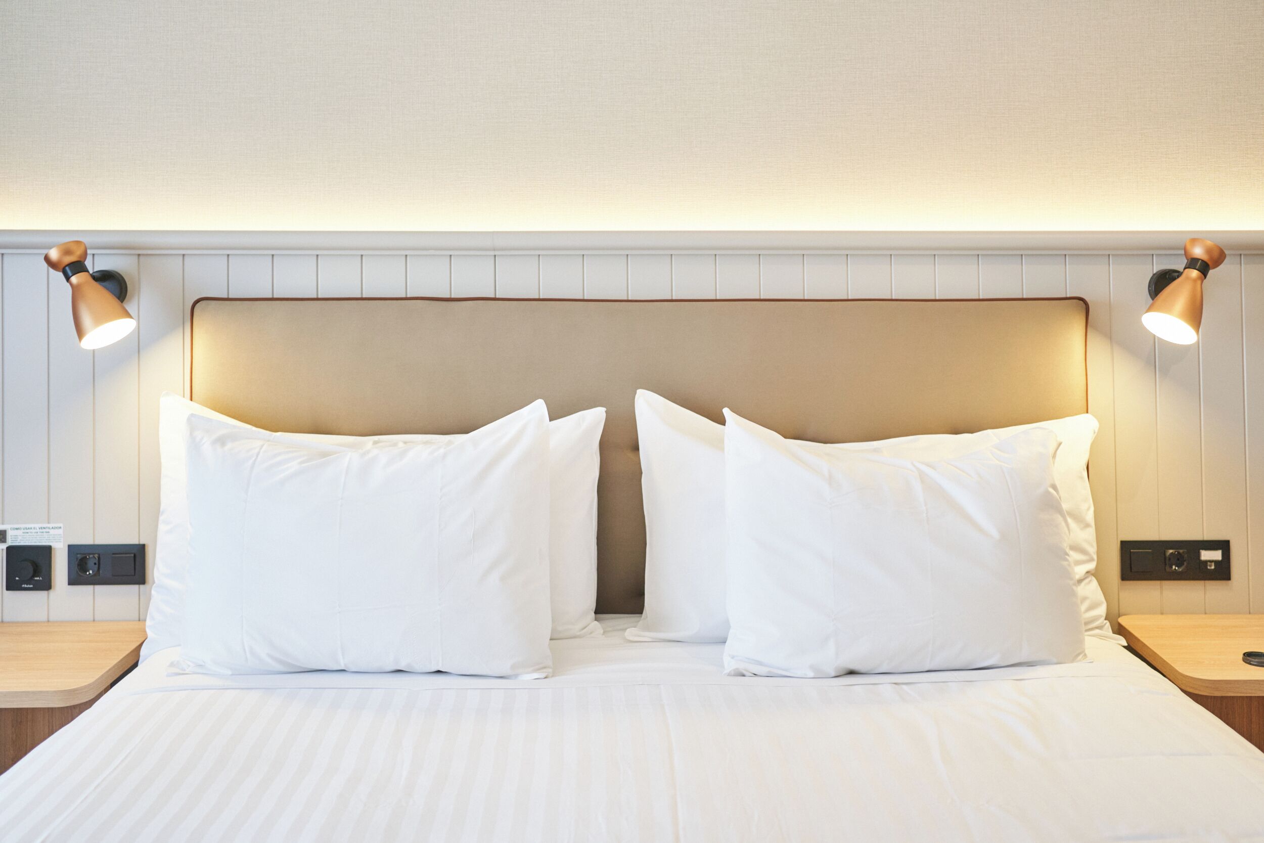 A hotel room with a large bed, two bedside tables, and wall-mounted lamps.