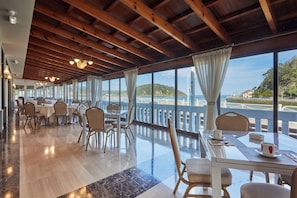 Un comedor amplio con vigas de madera, ventanas grandes y vistas al mar.