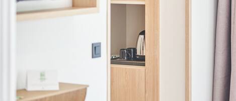 Una habitación con un armario de madera, una repisa con una tetera y una puerta con manija.