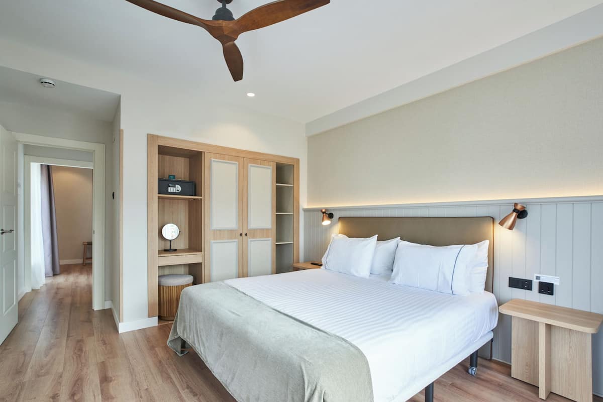 A bedroom with a bed, wooden wardrobe, bedside table, and a ceiling fan.
