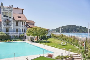 Un hotel con piscina, jardín y vistas al mar.