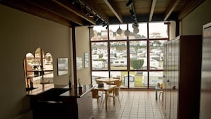 A kitchen with a dining area, large windows, and a view of a residential area. - Apartamentos Marina (Castrillon)