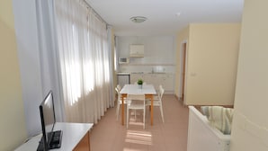 A compact kitchen with white cabinets, a microwave, and a small refrigerator. - Apartamentos Marina (Castrillon)