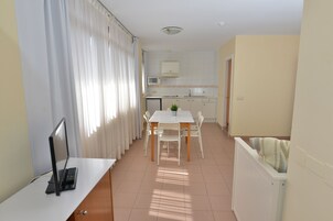 Cozinha compacta com armários brancos, micro-ondas e pequena geladeira.