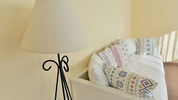A bed with patterned pillows and a white bedside table with a lamp.