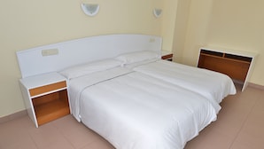 A neatly made bed with white linens, a wooden nightstand, and a built-in shelf unit. - Apartamentos Marina (Castrillon)
