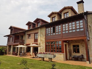 Una casa a due piani con facciata in pietra, ampie finestre e una veranda coperta con mobili da esterno.