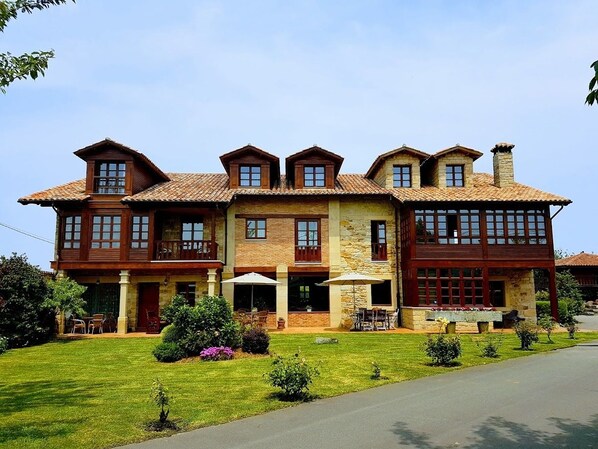Ein großes, mehrgeschossiges Haus mit einem weitläufigen Vorgarten und einer Sitzgelegenheit im Freien.