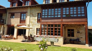 Un bâtiment en pierre de deux étages, doté d’un patio, d’un espace extérieur aménagé pour s’asseoir et d’une cheminée en pierre.