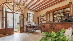 Une cuisine spacieuse avec des poutres en bois, un coin repas avec des chaises et un bar avec des étagères remplies de bouteilles.