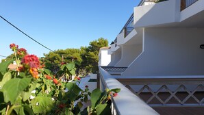 Un edificio bianco con un balcone e un giardino con fiori rossi.