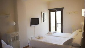 A hotel room with two beds, a TV, a window with a view, and a small white shelf. - Marbel (Cala Ratjada)