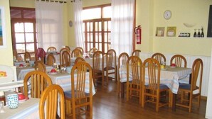 A dining area with wooden chairs and tables, a fire extinguisher on the wall, and a clock. - Marbel (Cala Ratjada)