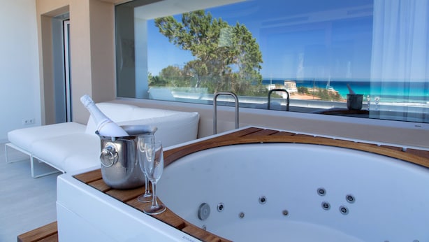 Un baño moderno con una bañera grande, un sofá blanco y vista al mar.
