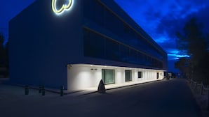 Un edificio moderno con un llamativo logotipo de Apple, una tienda con el rótulo "MINI SHOP" y una motocicleta estacionada afuera.
