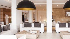 Una sala de estar moderna con sofás blancos, una mesa de centro y una lámpara colgante grande en negro y dorado.