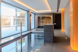 Una piscina cubierta, una piscina al aire libre, tumbonas