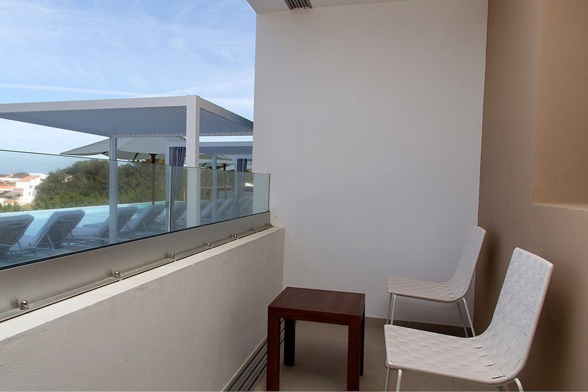 Un balcon doté d’une balustrade en verre, d’une petite table et d’une chaise blanche.