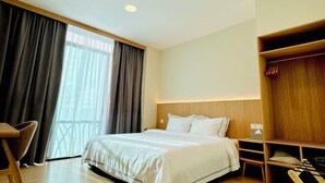 A hotel room with a bed, a wooden wardrobe, a desk, and a chair. - Eastwood Valley Golf & Country Club (Miri)