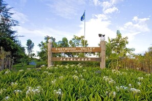 A sign for Eastwood Valley Golf & Country Club surrounded by lush greenery and flowering plants.