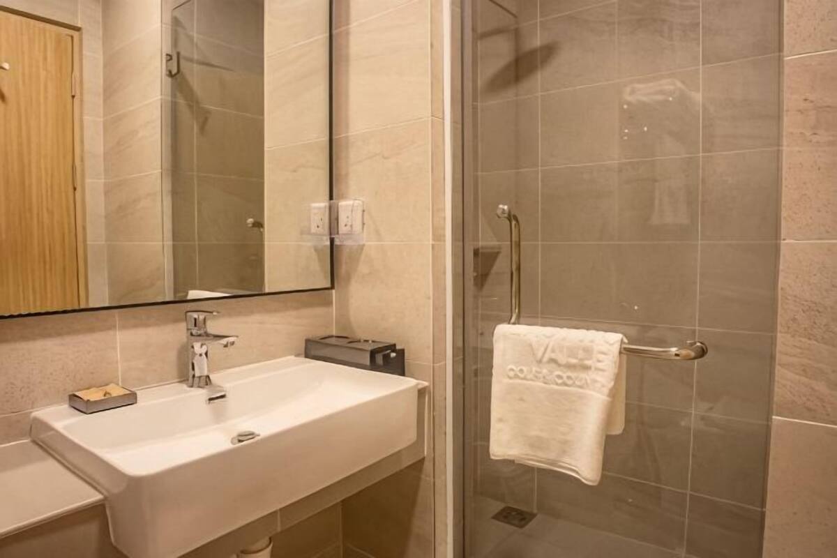 A bathroom with a sink, mirror, and shower.