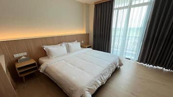 Ein Hotelzimmer mit einem großen Bett, einem Nachttisch und einem Fenster mit Vorhängen.