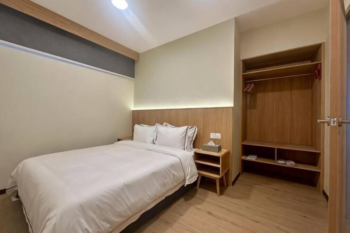 A bedroom with a bed, bedside table, nightstand, wardrobe, and built-in shelves.