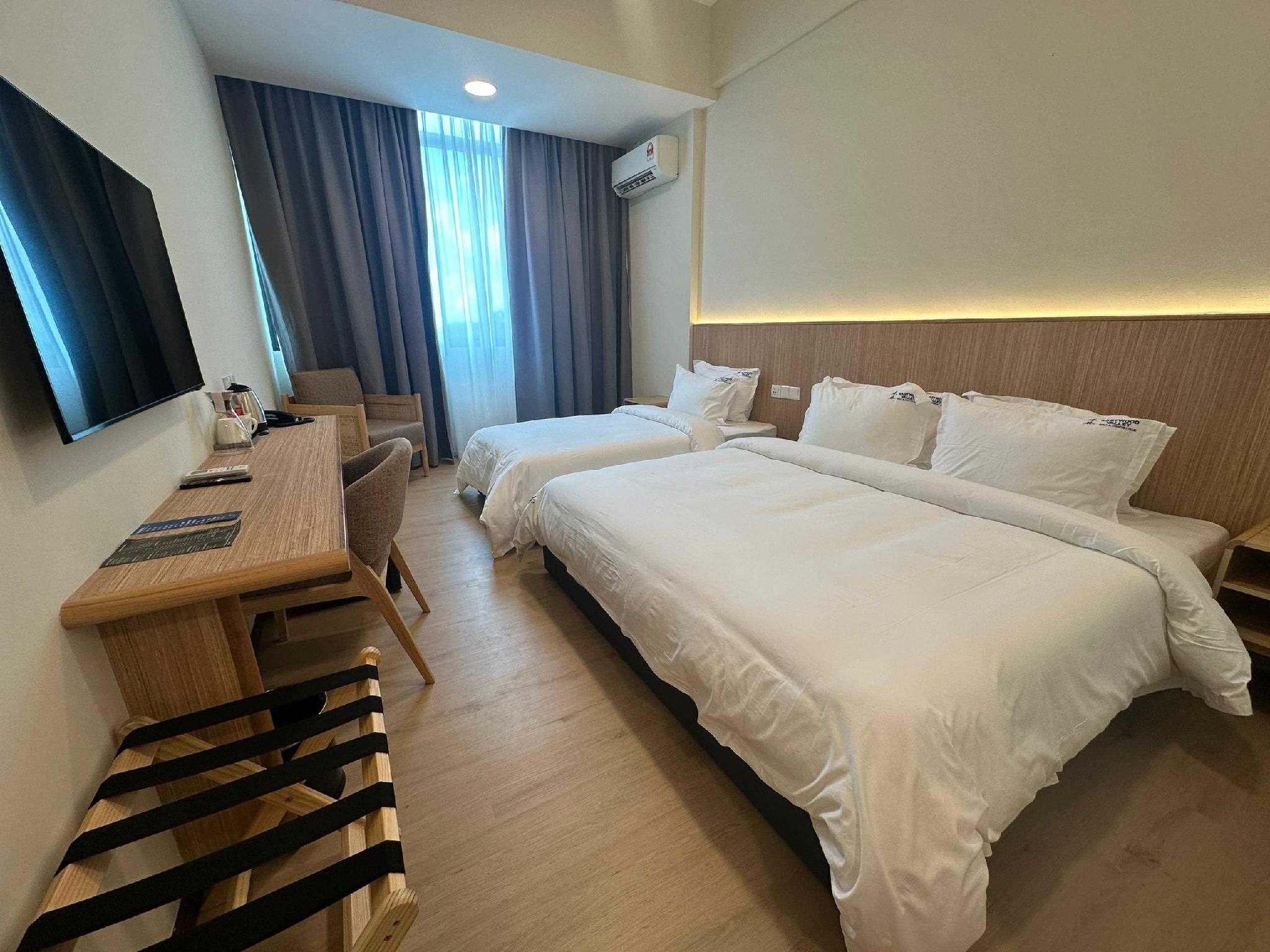 Une chambre d’hôtel équipée d’un bureau, de deux lits, d’une télévision et d’un appareil de climatisation.