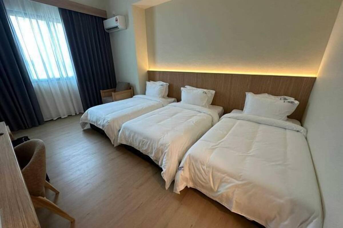 A hotel room with two beds, a desk, a chair, and a window with curtains.