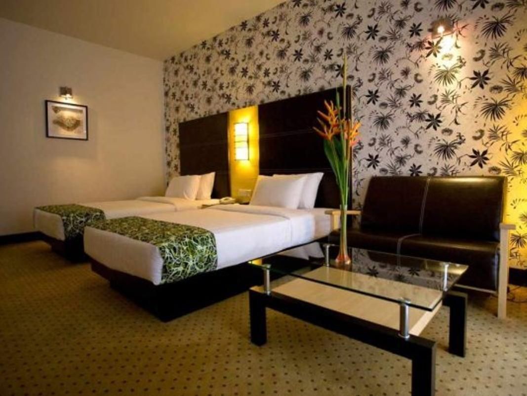 A hotel room with a bed, a sofa, a coffee table, and a wall with a floral pattern.