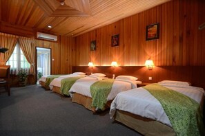 Ett hotellrum med fyra sängar, träväggar och ett tak med ett träådringsmönster.