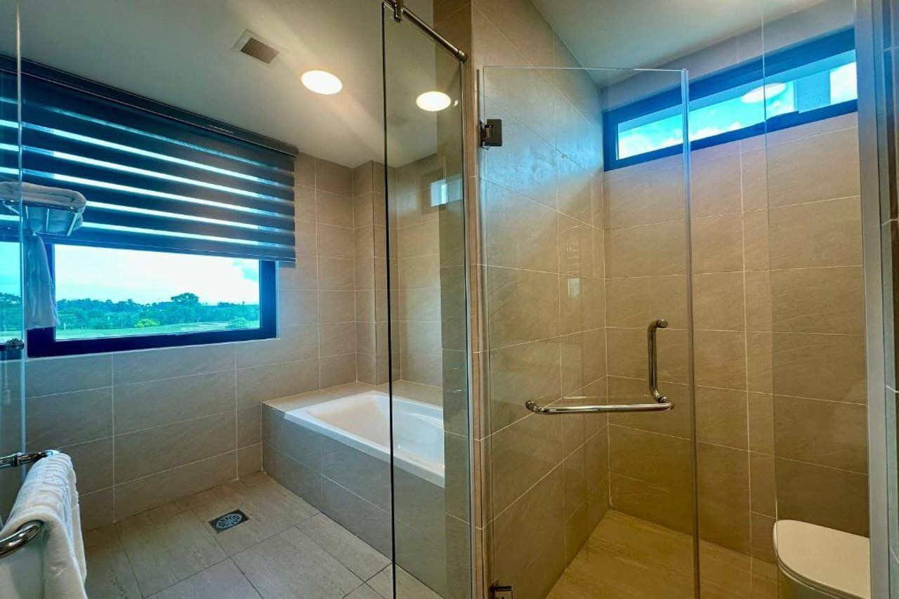 A modern bathroom with a glass-enclosed shower, a bathtub, and a toilet.