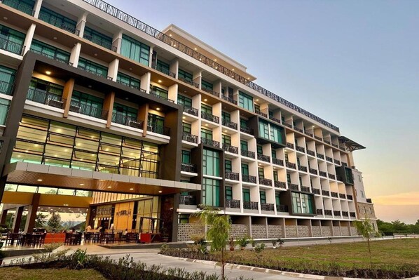 A multi-story hotel with a modern design, featuring balconies and a covered outdoor seating area.