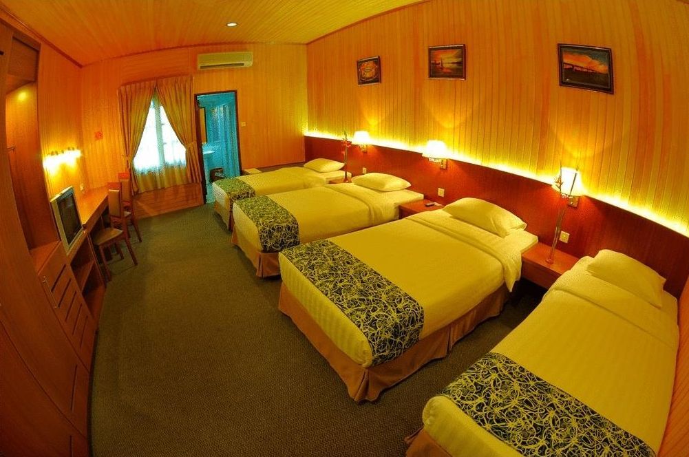 Hotellihuone, jossa on neljä sänkyä, työpöytä ja televisio.