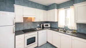 A kitchen with white cabinets, a black countertop, a microwave, a dishwasher, and a sink. - Villas Geisan (Ciutadella de Menorca)
