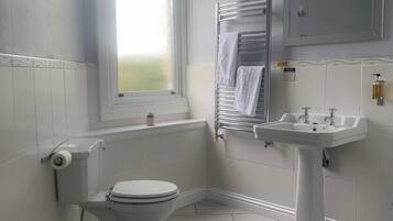 Un baño con inodoro, lavamanos, toallero y ventana.