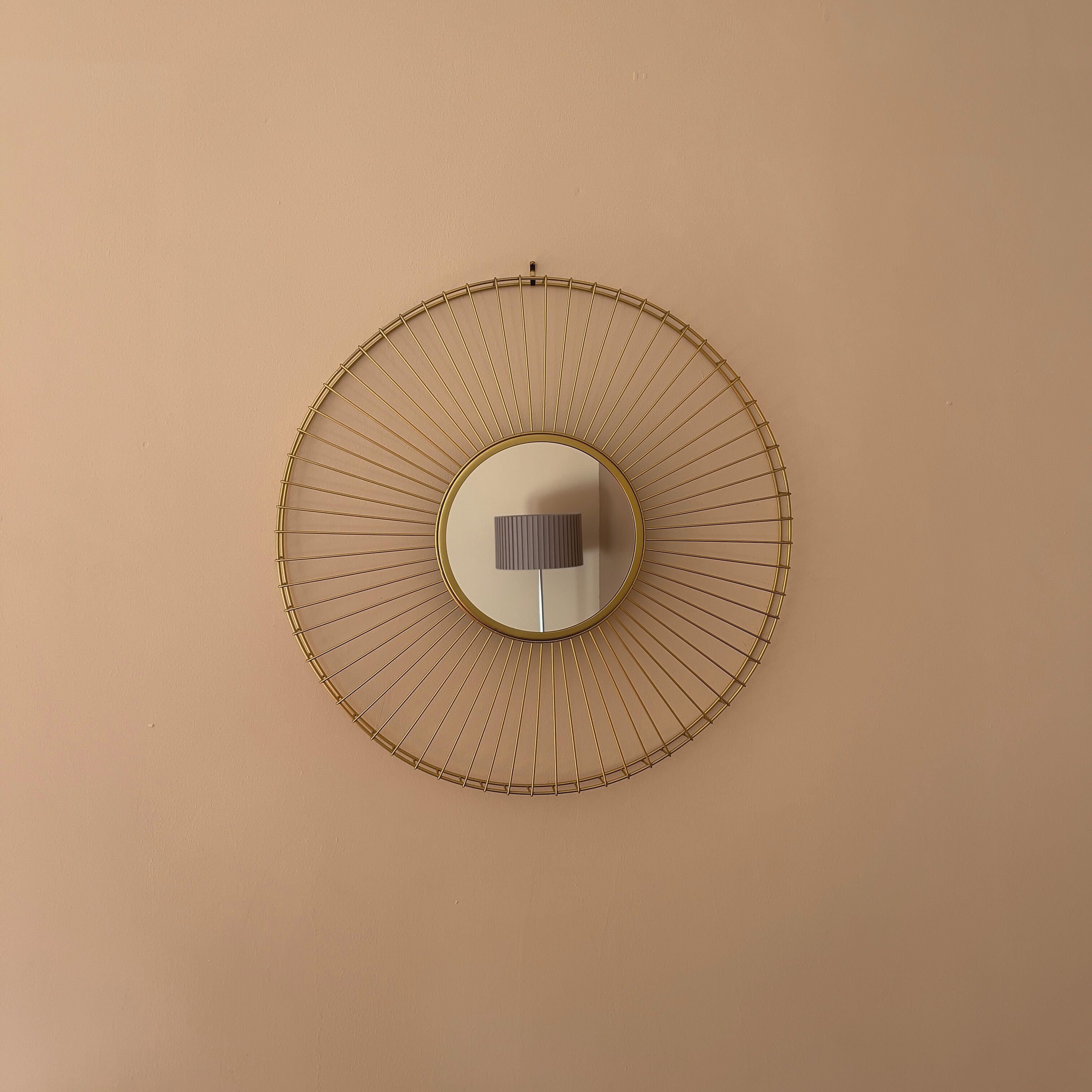 A wall-mounted circular mirror with a gold frame.