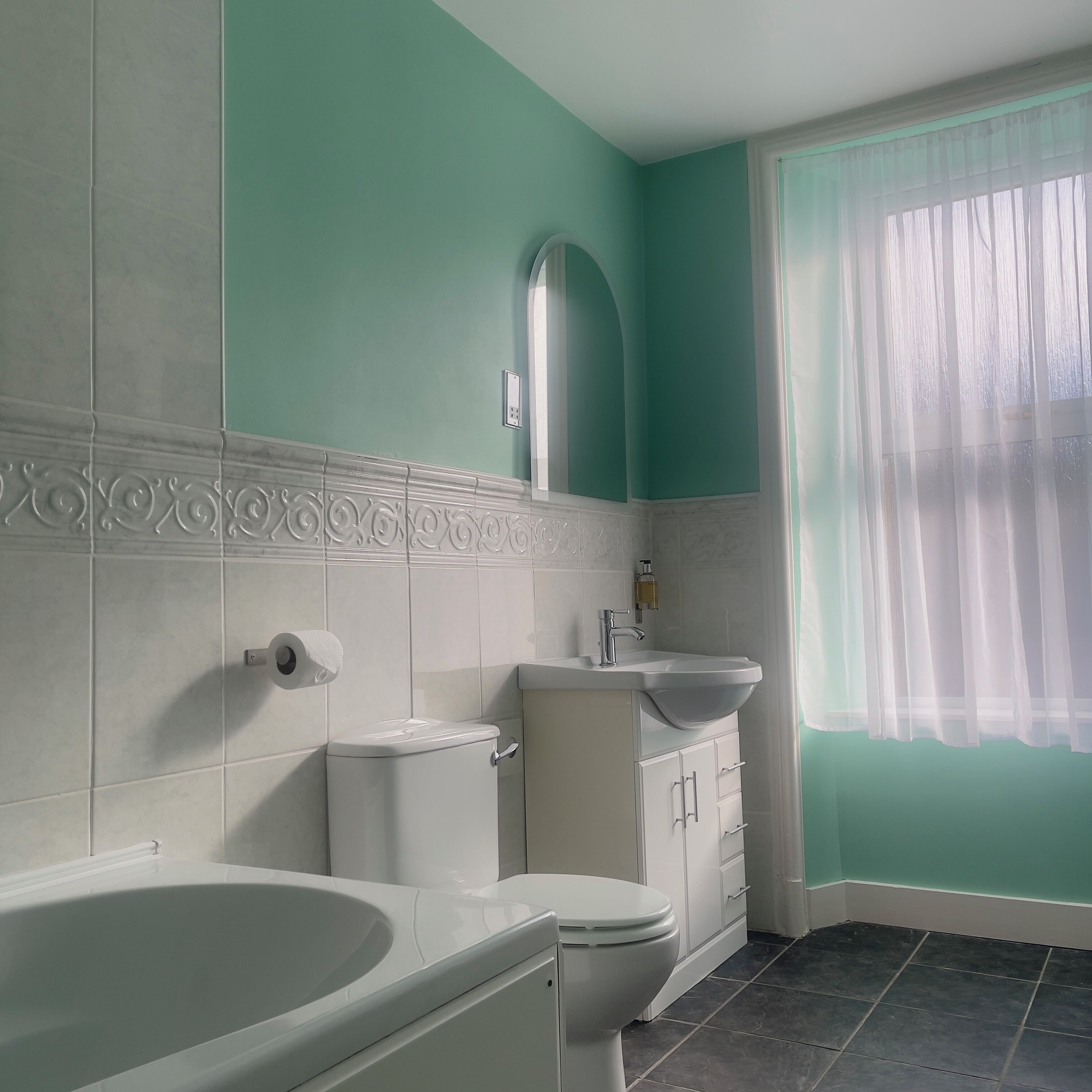 Een badkamer met een bad, toilet en wastafel.