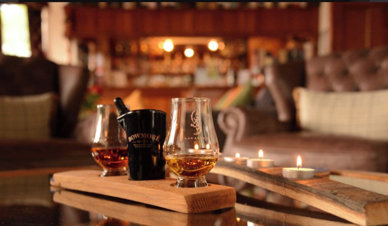 A bar setting with a wooden table displaying a bottle of whiskey, a glass, and a bottle of water.