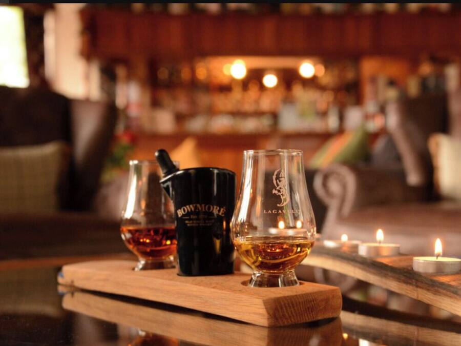 A bar setting with a wooden table displaying a bottle of whiskey, a glass, and a bottle of water.